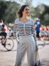 A woman wears striped cardigan and white jeans
